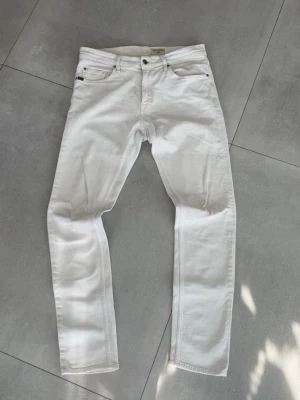 Tiger of sweden jeans  - Tja! Säljer ett par vita slim fit jeans från tiger of sweden med klassisk femficksdesign och knappgylf. Jeansen har raka ben och är tillverkade i bomull med lite stretch för extra skönhet. Perfekta för en clean och laidback look. Storleken är 32/34 och skicket är 10/10! Otroligt snygga vita jeans! Hör av dig vid mer frågor eller funderingar🤩mvh Ga