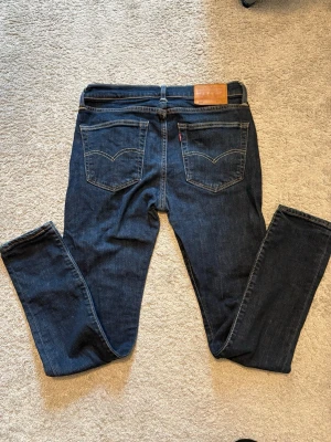Levi's 519 mörkblå jeans 32/32 - Snygga mörkblå Levi's 519 jeans med raka ben och klassiska bakfickor. Jeansen har en ikonisk läderpatch i midjan och kontrastsömmar. 