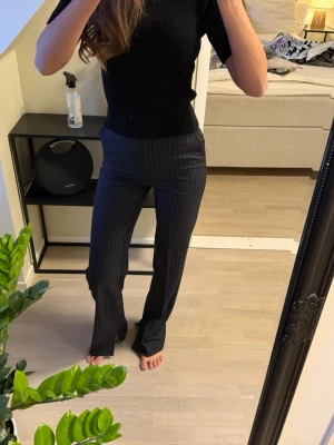 Mörkblå randiga kostymbyxor - Snygga mörkblå kostymbyxor med vita tunna kritstrecksränder. Byxorna har rak passform och hög midja, vilket ger en clean och stilren look. Perfekta att matcha med en enkel topp eller kavaj för en trendig outfit. Långa i benen och super snygga till klackar.