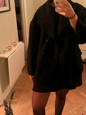 Oversized svart kappa från Maje Paris - Säljer en oversized svart kappa med bred krage och dubbelknäppning. Nypris ca 5000kr. OBS Lappen hänger löst. Bra skick i övrigt. Vet inte vilken storlek det är, men passar S-L beroende på passform