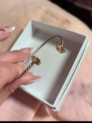 Caroline Svedbom Silvrigt armband med champangefärgade stenar  - Snyggt armband i silverfärgad metall med tvinnad design från Caroline Svedbom. Öppna ändar pryds av stora, guldiga pärlor som ger en lyxig känsla. Perfekt accessoar för att lyfta din outfit med lite extra bling använt endast en gång. . Armbandet är justerbart.  (Alla smycken skickas i fina askar) 