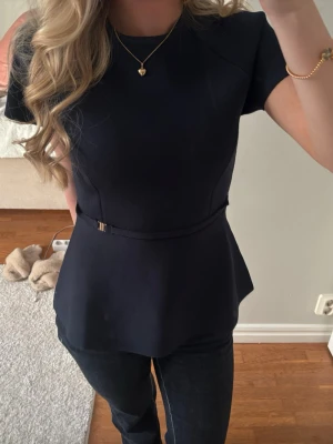 Mörkblå peplum topp - Snygg mörkblå peplum topp från Zara med korta ärmar och rund halsringning. Toppen har ett smalt bälte i midjan.