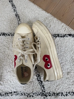 Converse x CDG Play vita låga sneakers - Säljer ett par vita Converse x Comme des Garçons Play sneakers med det ikoniska röda hjärtat med ögon på sidan. Klassisk låg modell med vita snören.