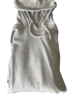 Ljusgrå hoodie med huva - En stilren ljusgrå hoodie med klassisk huva och dragsko. Hoodien har en avslappnad passform och är tillverkad i mjukt sweatshirtmaterial, perfekt för en chill och bekväm look. Inga synliga loggor eller tryck, enkel och clean design.