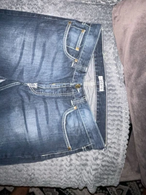 Blå jeans från Blend, raka ben - Säljer ett par klassiska blå jeans från Blend med raka ben och snygga slitningar. Jeansen har fem fickor, kontrastsömmar och är gjorda i 100% bomull. Perfekta för en avslappnad och stilren look.