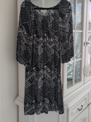 Svartvit mönstrad klänning Isolde - Svartvit kortklänning från Isolde med grafiskt mönster och löst sittande passform. Klänningen har trekvartsärm och rund halsringning.