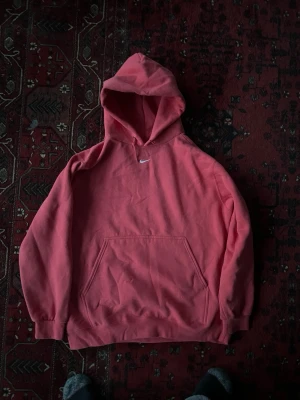 Nike College Hoodie röd - Säljer en snygg röd hoodie från Nike med klassisk huva och magficka. Liten vit Nike-logga broderad på bröstet. Hoodien har ribbade muddar vid ärmar och nederkant. Perfekt för en chill och sportig look.