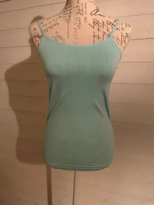 Ljusblå enkel linnetopp - Säljer en ljusblå linnetopp med smala axelband och figurnära passform. Toppen är ärmlös och har en clean, minimalistisk look som passar perfekt till jeans eller kjol. Materialet känns mjukt och stretchigt, vilket gör den bekväm att bära hela dagen.