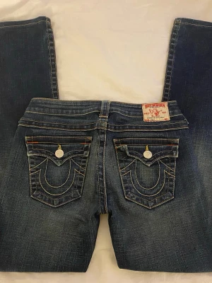 True Religion jeans | storlek 29 - Säljer ett par blå jeans från True Religion med ikoniska kontrastsömmar, passformen är något rakare. Hör gärna av dig om du har fler frågor!
