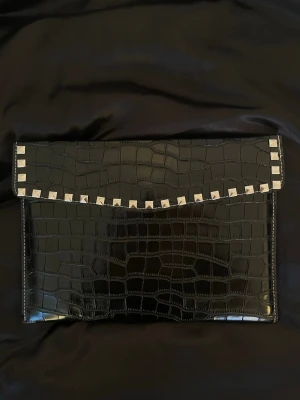 Datorfodral med silvernitar med krokodil mönster  - Stilrent datorfodral tillverkat av veganskt läder i vattentätt material. Fodralet stängs med knapp. Fodralet skyddar din dator effektivt samtidigt som det ger din outfit en extra touch. ⚜️ Storlek: 34 × 25 cm – passar svarta HP Chromebooks och andra datorer i liknande storlek. Köpt från ett UF företag men passade tyvärr inte min dator❤️