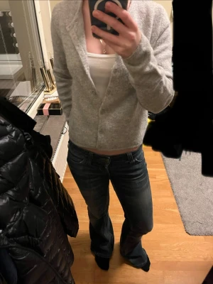 Grå kofta från Gina Tricot - Mysig ljusgrå kofta med rund halsringning och knäppning framtill. Tillverkad i ett mjukt, stickat material som passar perfekt till lager på lager. Enkel och stilren design utan synligt märke.