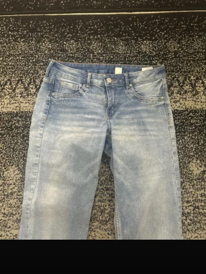 Ljusblå bootcut jeans  - Snygga ljusblå bootcut jeans med små silverfärgade nitar vid fickorna. Jeansen har en lätt tvättad look. Det finns ett flick och en annan sak kolla bild 3 och 5