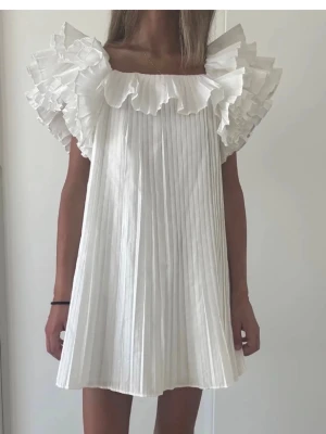 Vit plisserad kortklänning med volang - Supersöt vit kortklänning har använt den några gånger men är i jätte fint skick 