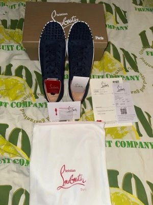Marinblåa Christian Louboutin sneakers - Snygga marinblåa sneakers från Christian Louboutin med klassiska nitar på tån och vit sula. Skorna har en låg silhuett och är tillverkade i mocka med svarta skosnören. Perfekt för dig som vill sticka ut med exklusiva detaljer. Kvitto och allt finns. Pris går att diskutera.