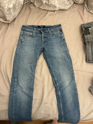 Blå raka jeans från Replay - Säljer ett par klassiska blå jeans från Replay med rak passform och fem fickor. Jeansen har snygga slitningar och kontrastsömmar som ger en avslappnad look. Perfekta till vardags och passar till det mesta. Materialet är mjukt denim i bomull.