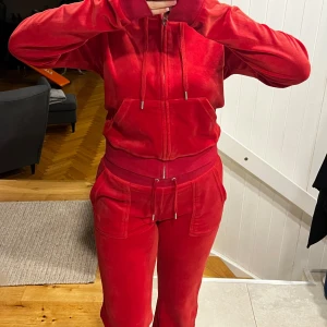 Röd mjukis set från Juicy Couture - Säljer ett par klassiska röda mjukisbyxor från Juicy Couture i storlek S samt matchande mjukis zip tröja i storlek M i mjuk velour. Byxorna har dragsko i midjan, raka ben och fickor på sidorna. Perfekta för en avslappnad och trendig look.❤️