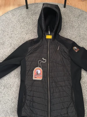 Svart vindjacka från Parajumpers - Snygg svart vindjacka från Parajumpers med luva. Använd få gånger. Den är som en helt ny, passar perfekt för våren räcker med en t shirt under. L j junior storlek men passar herr S. Pris kan diskuteras. Kvitto finns