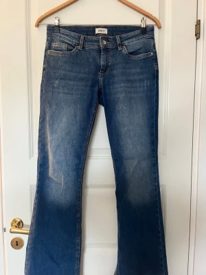 Blå bootcut jeans från ONLY - Snygga och sköna blå bootcut jeans från ONLY med klassisk femficksmodell och låg midja. Jeansen har en lätt tvättad look och är tillverkade i mjukt denimtyg, vilket gör dom väldigt stretchiga! Perfekta för en avslappnad och trendig stil.