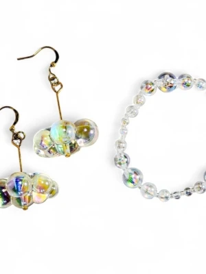 Paket! Iridescent pärlörhängen och armband regnbåge moln  - Unika örhängen från Strössel med iriserande pärlor i klusterdesign. Pärlorna har en skimrande, regnbågsliknande yta och hängs på guldpläterade krokar. Perfekt för dig som vill sticka ut med coola accessoarer. 