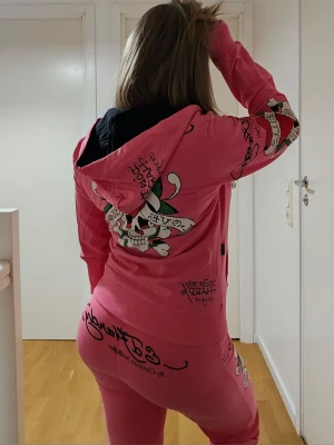 Ed hardy sett (byxor + tröja) - Rosa Ed Hardy-set i klassisk 2000-talsstil med lågmidjad passform och strassdetaljer. Riktigt Y2K-plagg, jätte gulligt.  Märkt XL men sitter mer som S/M beroende på hur man vill att det ska sitta. Nyskick – knappt använt och alla stenar är kvar.  Runt 2500–3000 i nypris.