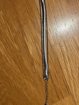 Silvrigt kedjearmband i metall - Snyggt armband i silverfärgad metall med tre olika kedjedesigner, en slät och en med små kulor. Justerbar längd med förlängningskedja. Perfekt accessoar för att lyfta din stil.