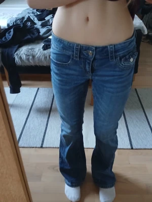 Blå bootcut jeans med låg midja - Säljer ett par klassiska blå bootcut jeans med låg midja fickor. Jeansen har snygga sömmar. Perfekta till sneakers eller boots och ger en avslappnad men trendig look.