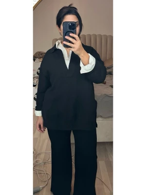 Svart oversized stickad tröja - En svart, oversized stickad tröja med v-ringad krage och långa ärmar. Tröjan har en avslappnad passform och är perfekt att bära över en skjorta för en cool lager-på-lager look. Slits på båda sidor. Nopprig.