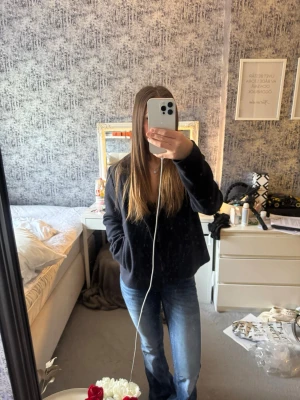 Svart kappa från Saint Tropez - Stilren svart kappa från Saint Tropez med klassisk krage och knäppning framtill. Kappan har en beige insida och raka fickor på sidorna. Perfekt för dig som vill ha en enkel men snygg look till hösten eller vintern.