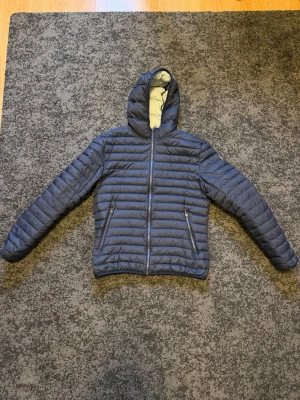 Colmar mörkblå dunjacka - Säljer en tunn mörkblå dunjacka från Colmar i storlek 50. Den har ett pyttelitet hål som är lagat (se sista bilden) men annars i perfekt skick. Nypris är 3500kr. 