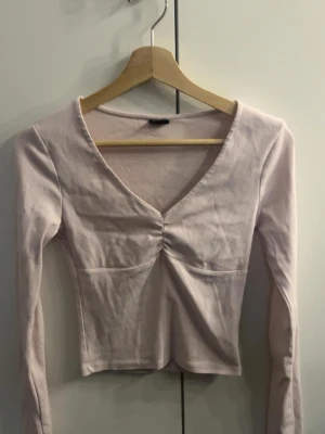 Ljusrosa långärmad topp Gina Tricot - Supersöt ljusrosa långärmad topp från Gina Tricot med v-ringning och rynkdetalj framtill. 