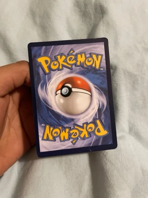 Charizard VMAX Pokémonkort - Säljer ett Charizard VMAX Pokémonkort med holografisk yta och färgstark design. Kortet har motiv av Charizard i svart och orange med eldflammor i bakgrunden. Perfekt för samlare eller Pokémonfans som vill utöka sin kortsamling. Pris kan diskuteras.