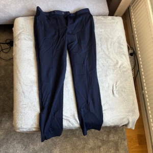 Mörkblå kostymbyxor herr, kavaj mörkblå - Snygga mörkblå kostymbyxor med klassisk rak passform och pressveck. Byxorna har hällor för bälte, två sidofickor fram och två bakfickor med knapp. Perfekta för en stilren och dressad look. Samt en mörkblå kavaj 