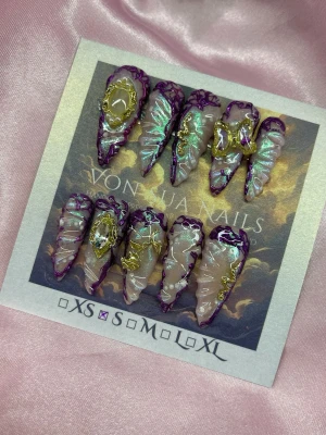 Myth (S);Long Stiletto - Unika handgjorda press-on naglar i lila och ljusbeige med skimrande detaljer, 3D-effekter och guldfärgade  charms. Naglarna har long stiletto form och cool design med holografiska inslag. Perfekt för dig som vill sticka ut med en edgy look.S: 15 mm, 11,5 mm, 12 mm, 11 mm, 9 mm 