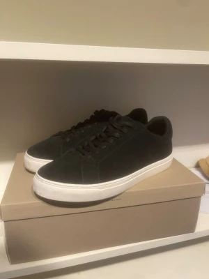 sneakers med vit sula - Stilrena sneakers med lågt skaft och vit sula. Skorna har en minimalistisk design med svarta skosnören och ovandel i mockaliknande material. Perfekta för dig som gillar en clean look och vill ha något som funkar till det mesta.