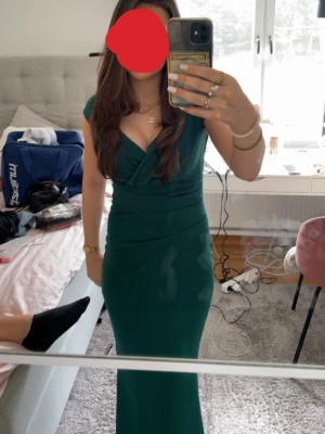 Grön långklänning med v-ringning - Säljer min fina balklänning som jag hade 2025, haft på mig den 1 gång och den är i mycket god skick utan några skador. Det är en elegant grön långklänning med djup v-ringning och figurnära passform. Klänningen har breda axelband som man kan ha så som jag har det eller off shouder och markerad midja som framhäver siluetten. 