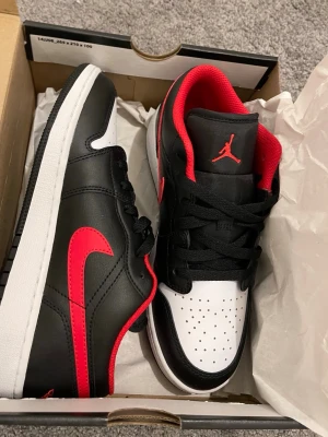 Nike Air Jordan 1 Low svart/röd/vit - ✨Nike Air Jordan 1 Low sneakers i svart, rött och vitt. Strl 38. Oanvända med orginal paket✨