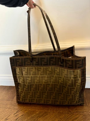 Fendi shoppingväska i brunt monogram - Cool shoppingväska från Fendi i brunt med klassiskt FF-monogram över hela väskan. Skador på handtaget men går nog att ordna hos skräddaren tex.