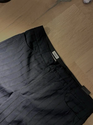 Kostymbyxor från Filippa k - Blå/ svarta randiga kostymbyxor från Filippa k i storlek s. Raka ben med lite utsvängd, kortare modell. Jag är 164 till referens. 