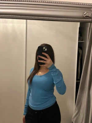 Blå ribbad långärmad topp Monki - Säljer en ljusblå ribbad långärmad topp från Monki. Toppen har en rundad, djup ringning och är tillverkad i mjuk stretchig bomullsmix. Perfekt att styla med jeans eller kjol för en enkel och snygg look.