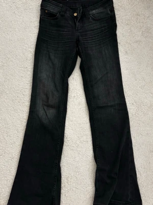 Gråa bootcut jeans från weekday  - Säljer ett par svarta bootcut jeans från weekday med klassisk femficksmodell och knappgylf. Jeansen har en lätt tvättad look och är tillverkade i mjuk denim med lite stretch för extra komfort. Perfekta för dig som gillar en retroinspirerad stil. 