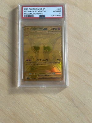 Mega Charizard X EX Pokémonkort - Obs ej orginal. Säljer ett samlarkort, Mega Charizard X EX från Pokémon, japansk version från 2025. Kortet är guldglänsande och graderat av PSA som GEM MT 10. Kortet ligger i ett genomskinligt plastskydd och har exklusiv design med japansk text.
