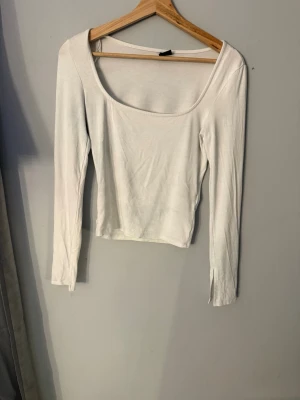 Vit långärmad tröja  - Säljer en enkel och stilren vit långärmad topp med croppad passform och bred, rundad urringning. 