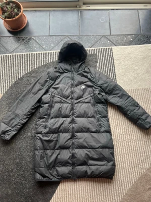 dunjacka från Nike - Hej! Säljer min svarta dunjacka jacka från Nike. Den är använd men inte så mycket och är i bra skick. Väldigt skön och varm. Säljer den då  jag inte använder den så mycket längre.