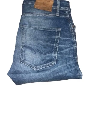 Blå jeans från Jack and jones - Säljer ett par klassiska blå jeans från Jack and Jones  med femficksdesign och snygga slitningar. Jeansen har en rak passform och är gjorda i bomullsdenim. Perfekt för dig som gillar tidlös stil och vill ha ett par jeans som funkar till det mesta.