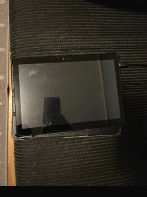 Svart surfplatta med fodral - En svart surfplatta med stor pekskärm och tillhörande svart fodral i konstläder. Plattan har en rektangulär form och en kamera på framsidan. Perfekt för streaming, surf och appar. Laddas via kabel på sidan.lenovo tab m10 surfplatta med 32 gb med en spika på skärmen ser på bilden