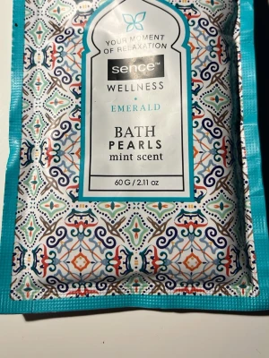 Sence Wellness Bath Pearls mint - Sence Wellness Emerald Bath Pearls med mintdoft. Kommer i en färgglad, mönstrad förpackning med blå, orange och vita detaljer. Perfekt för ett avslappnande bad och ger en fräsch känsla med mintarom.