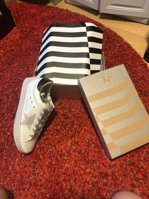 Vita sneakers från GGD  - Stilrena vita sneakers från Sneakerstar med grå stjärndetalj på sidan och svart hälparti. Skorna har vita snören och en slitstark sula med textur. Tillverkade i läder med klassisk låg profil och snygg design som passar till det mesta.      (SKORNA ÄR HELT OANVÄNDA) 