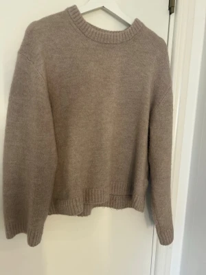 Beige stickad tröja Gina Tricot - Mysig beige stickad tröja från Gina Tricot i ullblandning. Tröjan har rund halsringning, ribbade muddar och en avslappnad passform. Perfekt för lager på lager under kyliga dagar.