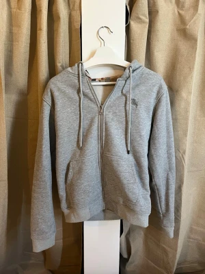 Burberry zip-hoodie med rutigt foder - storlek M - Elegant och bekväm ljusgrå hoodie från Burberry med dragkedja framtill och justerbar huva. Den klassiska Burberry-rutan pryder insidan av huvan och öppningen, vilket ger ett exklusivt och igenkännbart uttryck.  ✔ Storlek: M men liten i Storlek! ✔ Färg: Ljusgrå ✔ Modell: Zip-up med fickor framtill ✔ Detaljer: Broderad logga på bröstet, ribbade muddar och nederkant ✔ Skick: Metall bit på en av snörena har lossnat annars väldigt bra skick!