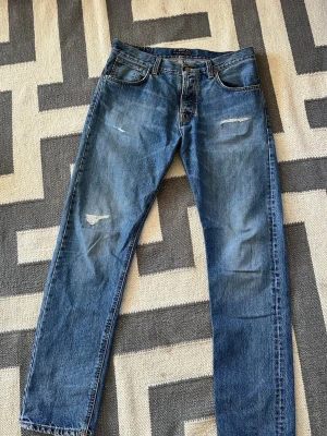 Nudie steady eddie med slitningar - Ett par steady eddie från nudie jeans med snygga slitningar! Fint skick👌                     Storlek w34 l32, men passar snarare w33.     Hör av er vid frågor! Priset är diskuterbart!